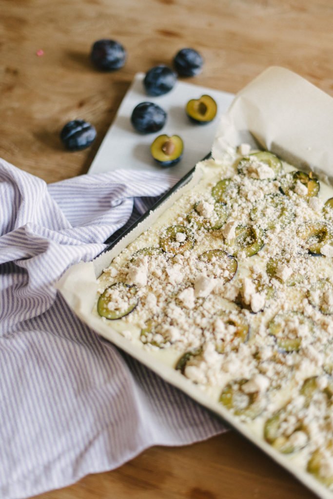 Noch nicht gebackener Pflaumenkuchen auf dem Blech mit Streuseln