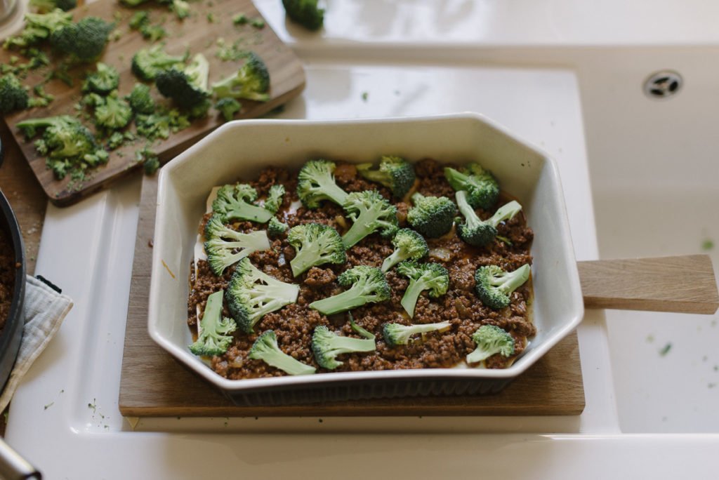 Brokkoli auf der Lasagne verteilen