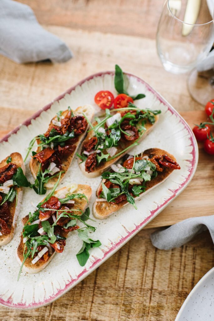 Vegetarische Bruschetta mit getrockneten Tomaten und Oragano auf einer Platte angerichtet.