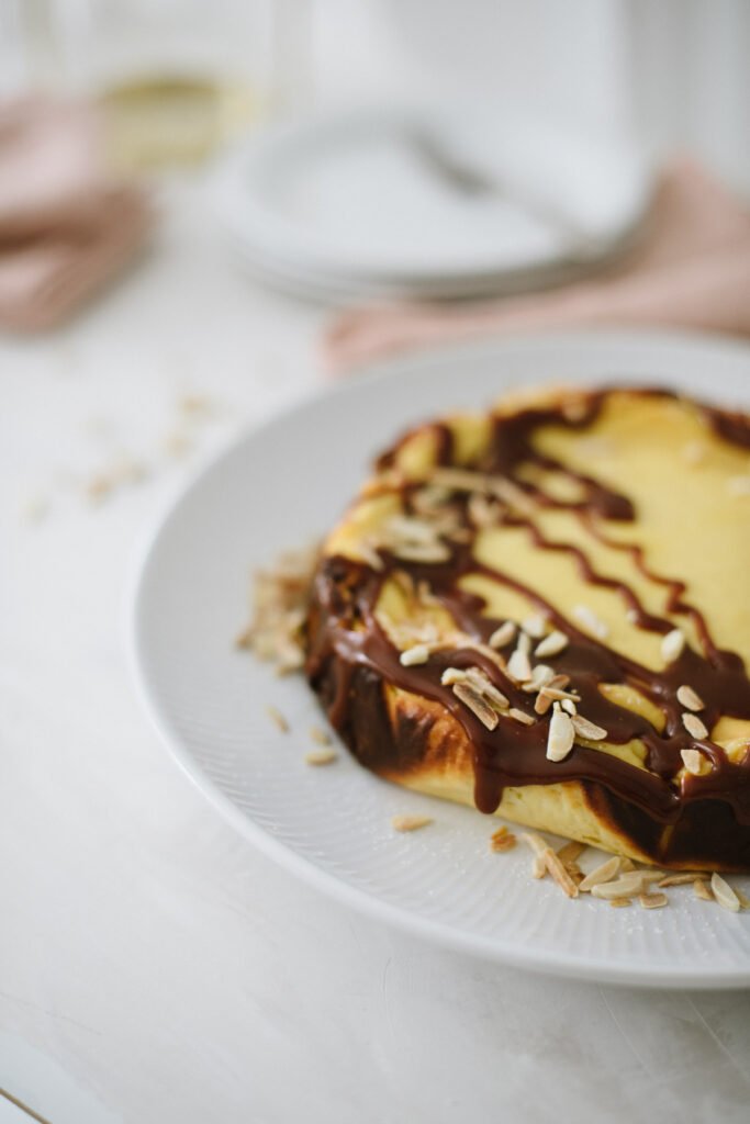 Einfacher Käsekuchen, ideal für Anfänger. Kleines Extra: Topping mit Karamellsauce und Mandelsplitter. Perfekt für den Sonntag, schnell gebacken.