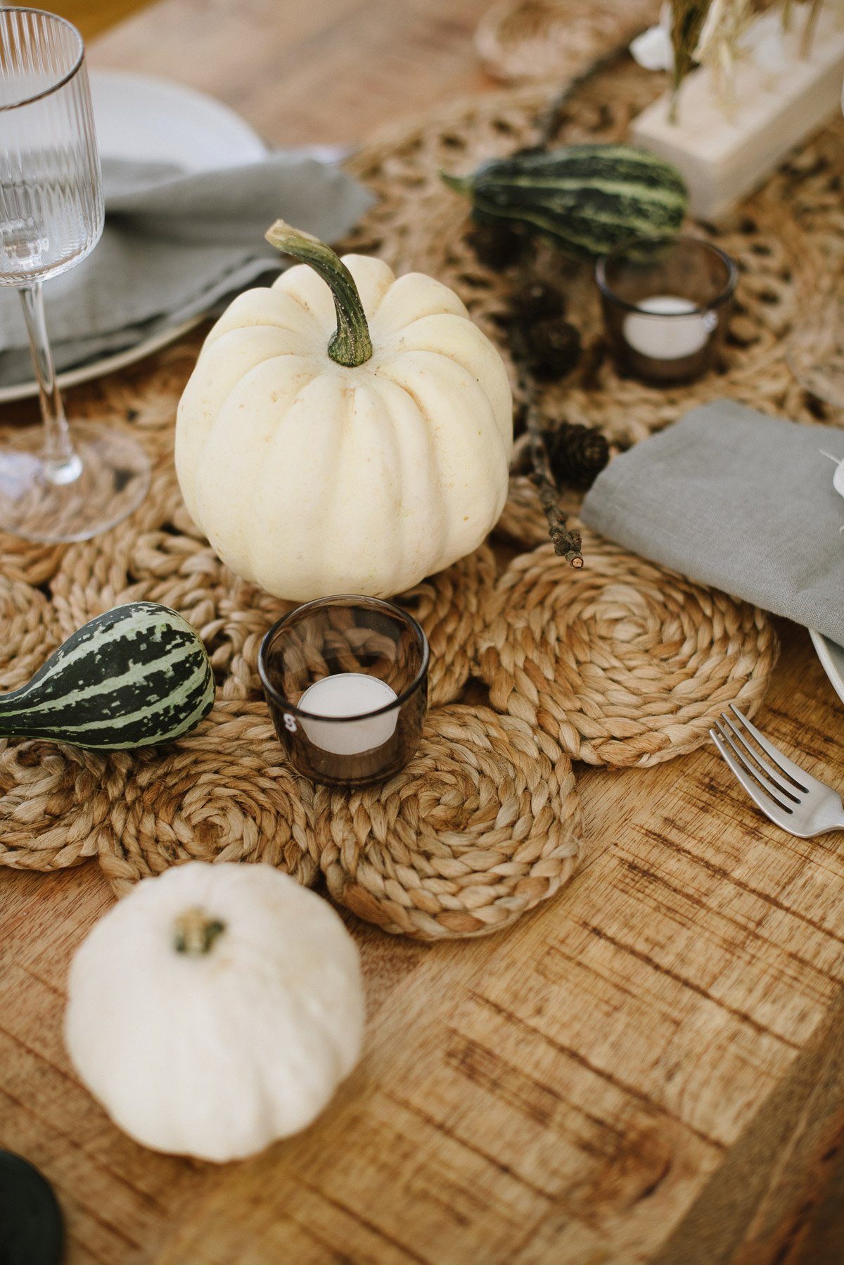 Herbsttisch gedeckt mit weißen und grünen Kürbissen