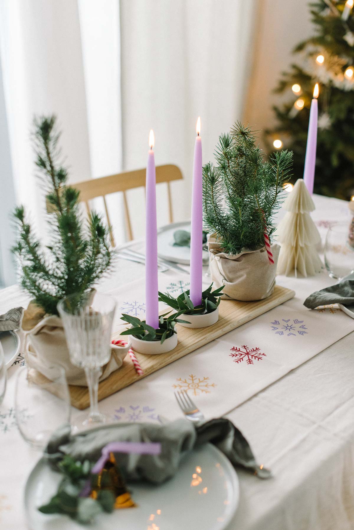 weihnachtliche gedeckter Tisch mit lila Kerzen und bunten Schneeflocken