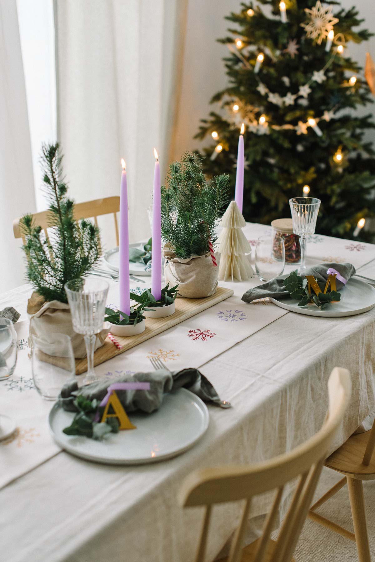 weihnachtliche gedeckter Tisch mit lila Kerzen und bunten Schneeflocken